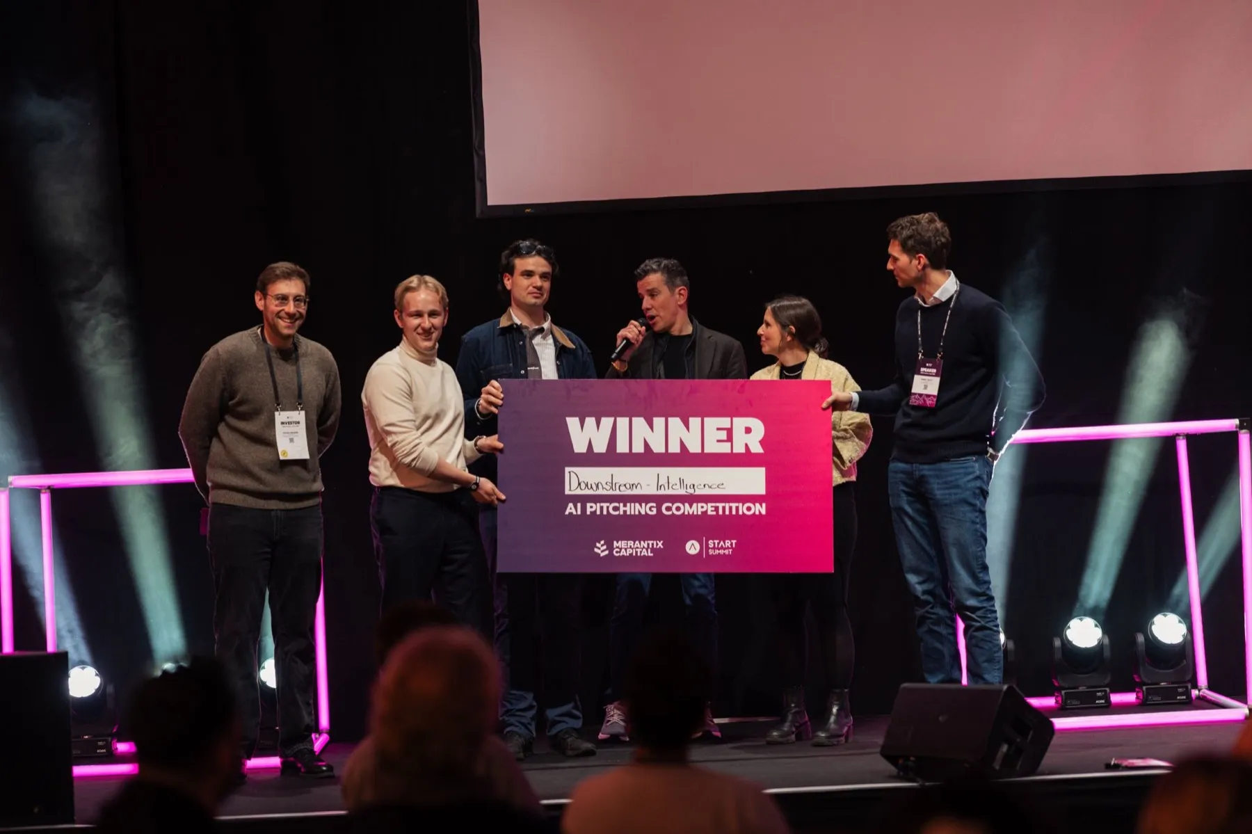 The Downstream Intelligence team on stage at START Summit holding a large WINNER board; Raffael is second from the left in a cream sweater.